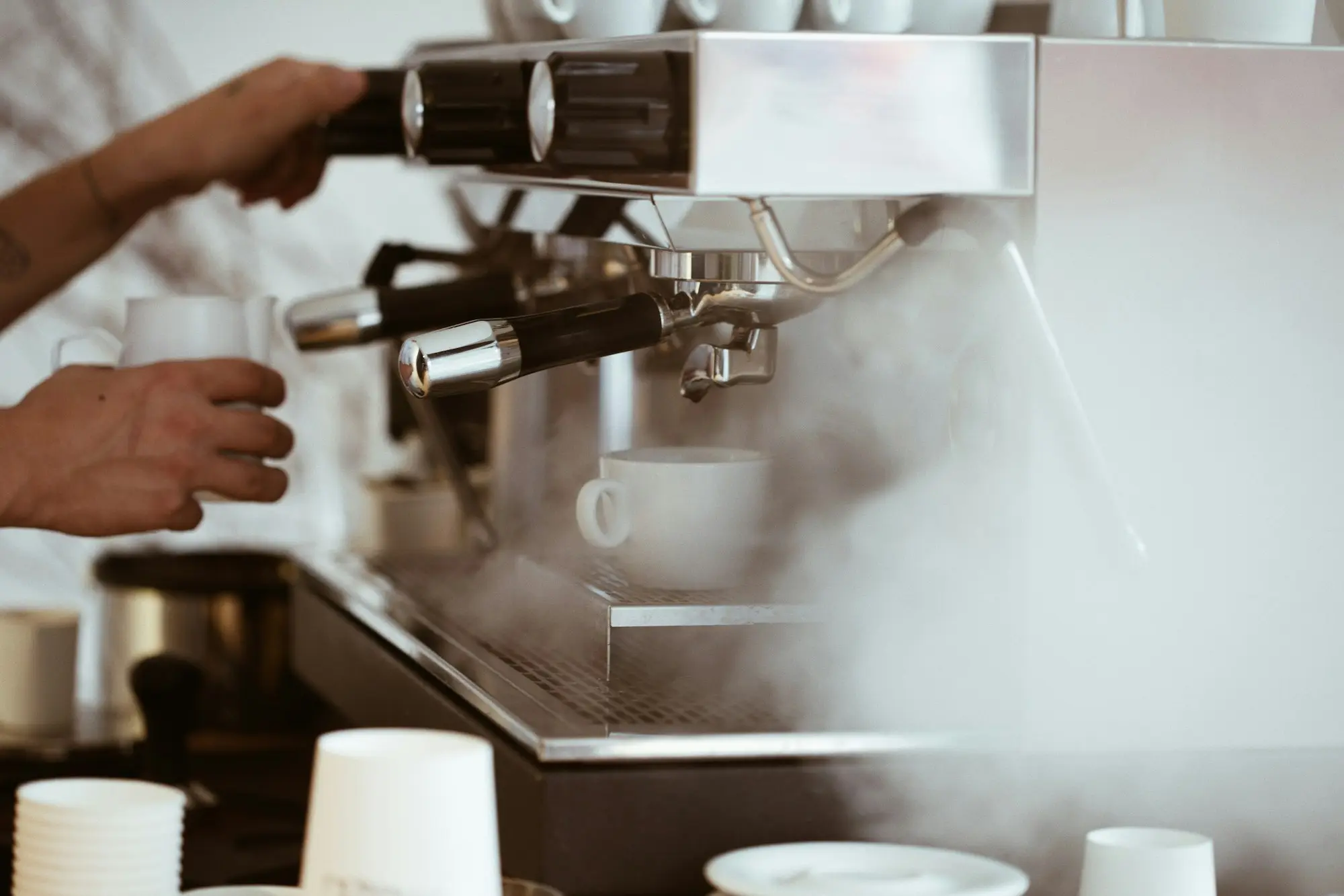 Café owner standing beside a new espresso machine behind a timber counter