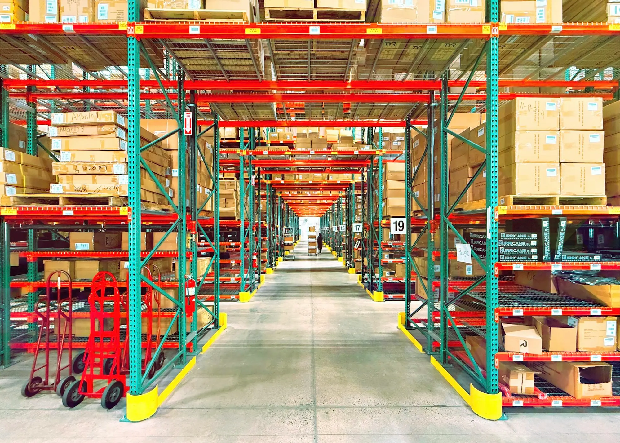 Shop owner counting cartons of new stock in a tidy back stockroom